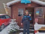 Frau mit Kaffeetasse vor Blockhütte