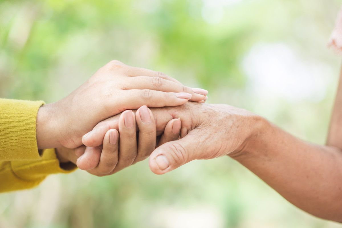 Junger Mensch hält die Hand von älterem Mensch