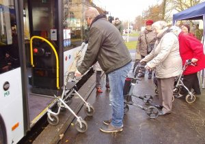 Der Mobilitätstrainer steht mit dem Rollator vor der Tür des Busses und ist einen Schritt nach hinten getreten.