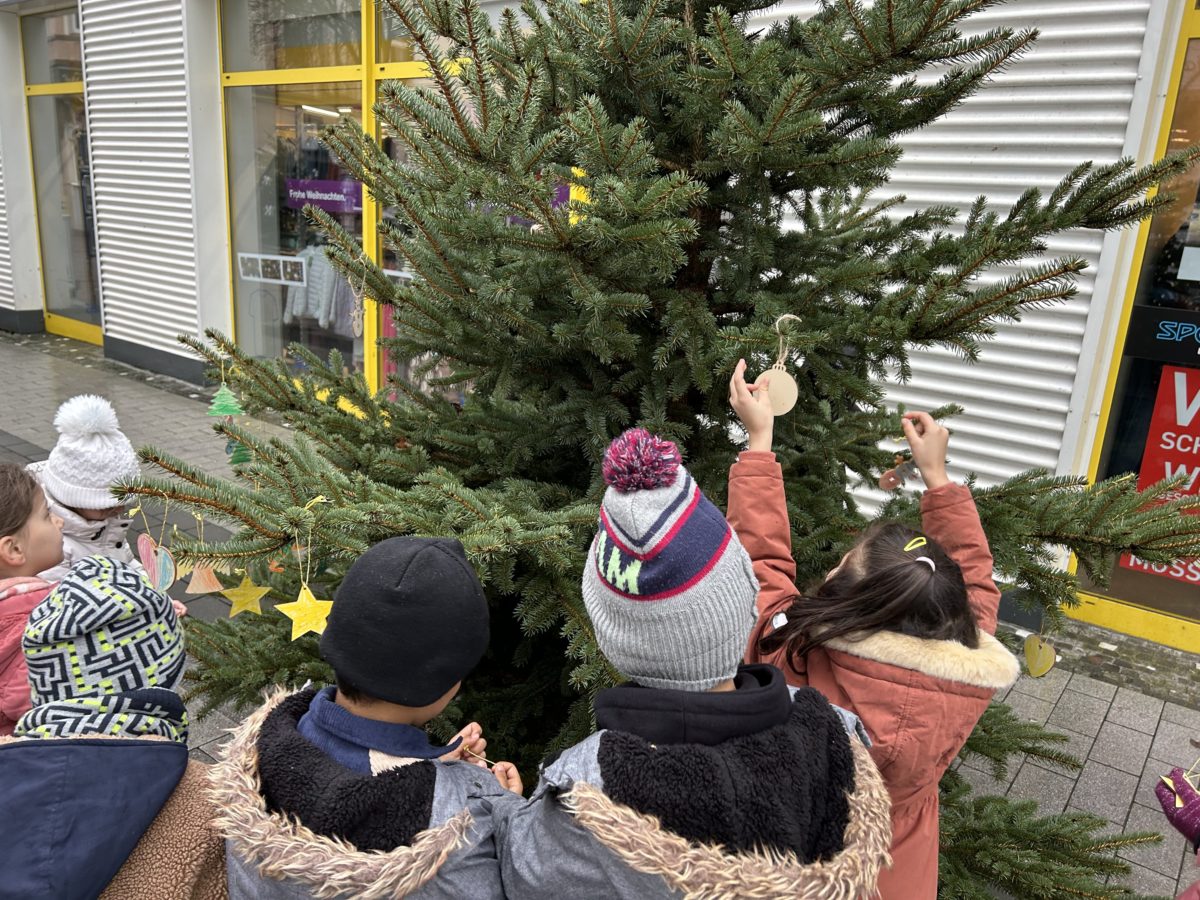 Kinder beschmücken die Weihnachtsbäume in der Hertener Innenstadt