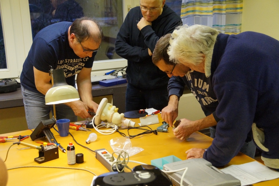 Foto: Das Repair-Team und ein Gast reparieren eine Tischlampe